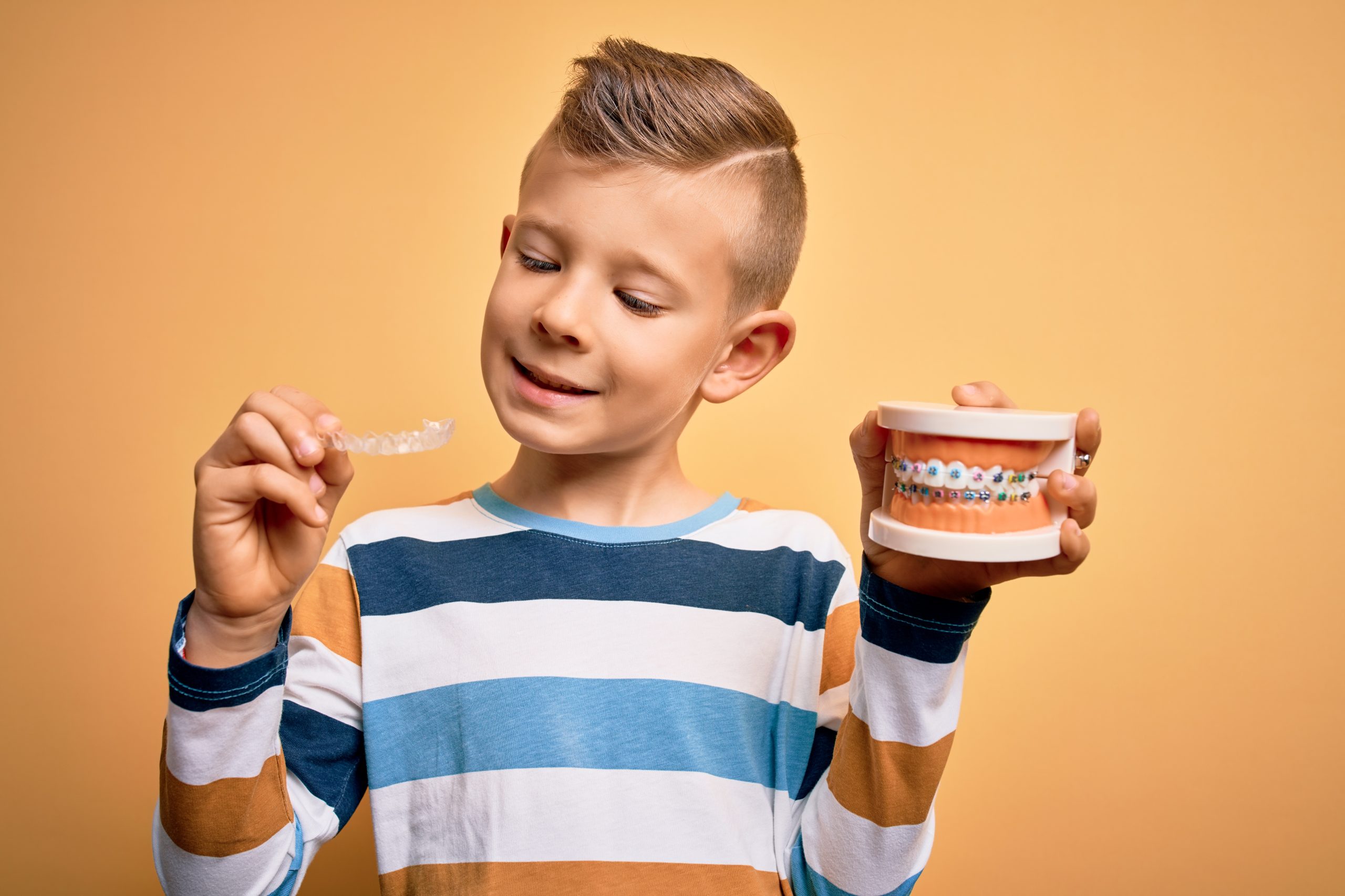 young boy holding dentures