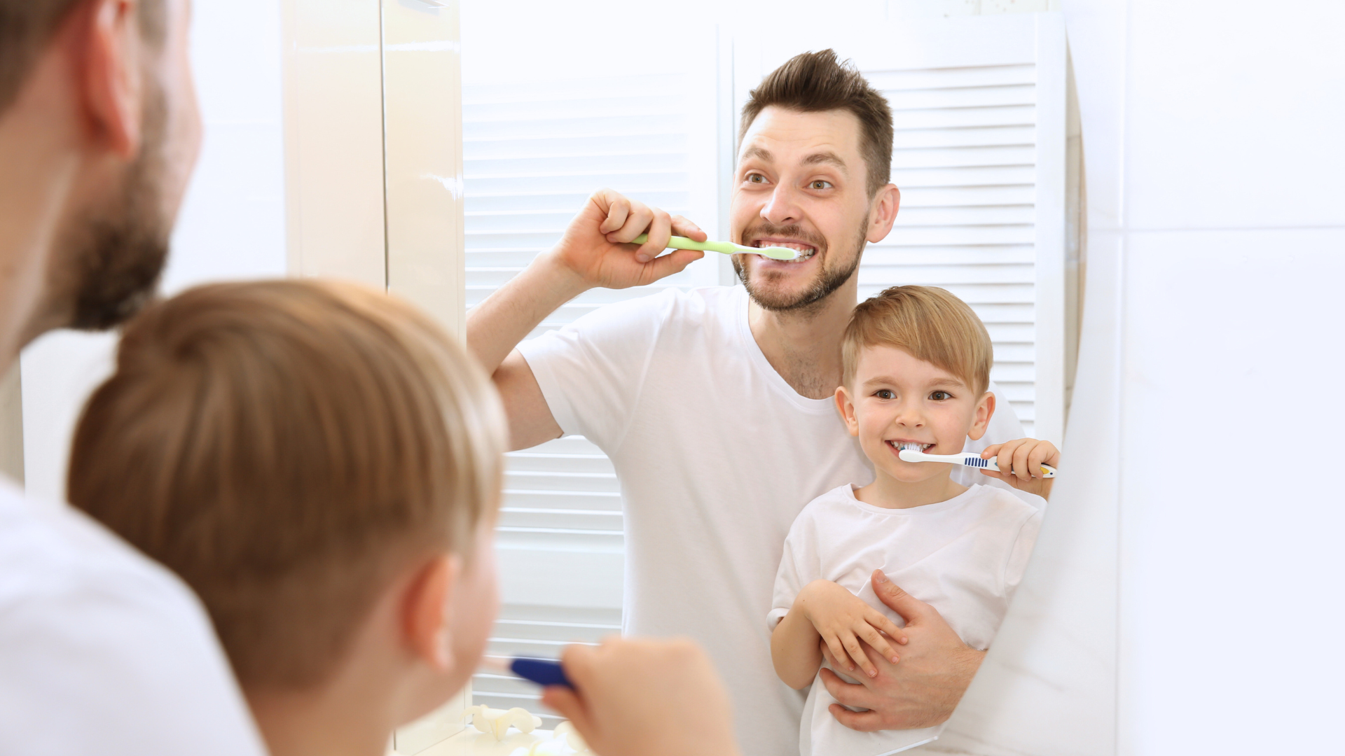 A Father teaches a son how to brush his teeth, promoting healthy dental habits.